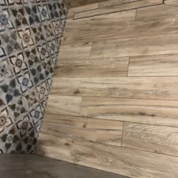 Łazienka wykończona płytkami imitującymi drewno na ścianie i podłodze z odpływem liniowym, kontrastująca ściana z dekoracyjnymi płytkami w stylu retro.