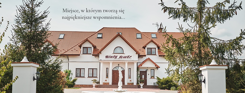 Elewacja budynku z czerwonym dachem, białą fasadą i napisem Biały Dwór, otoczona zielenią i kolumnami z latarniami.