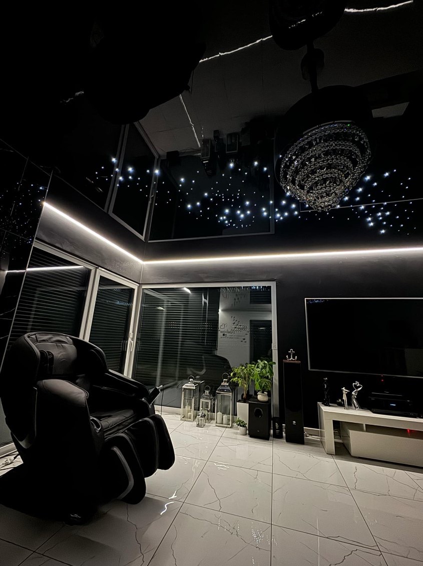 Czarne, błyszczące wnętrze z fotelem masującym, sufitem z efektem gwiazd, kryształowym żyrandolem i ledowym oświetleniem liniowym.