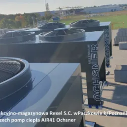 Kaskada trzech przemysłowych pomp ciepła Ochsner AIR41 na dachu hali produkcyjno-magazynowej Rexel S.C. w Paczkowie, widoczne także panele słoneczne.