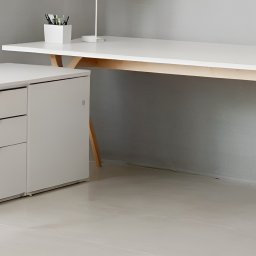 KROYEE Sp. z o.o. - Minimalistyczne, białe biurko z drewnianymi nogami i szafką z trzema szufladami w jasnym, nowoczesnym wnętrzu.