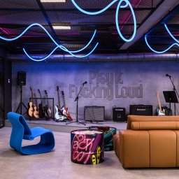 TENGO DESIGN - Kreatywna aranżacja biura z mini sceną muzyczną: gitary, wzmacniacze, neonowe oświetlenie, designerskie meble. Industrialny styl z nutą rock'n'rolla.