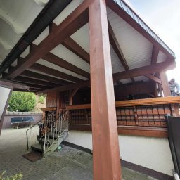 Usługi dekarskie Marcin Jankowski - Drewniana konstrukcja z białym podsufitkiem i metalową rynną, widoczny fragment dachu z blachy oraz pracownik na górze.