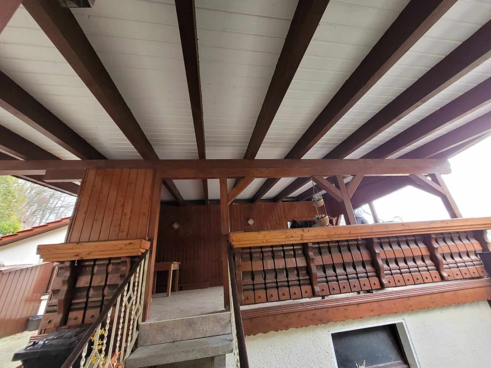 Drewniana konstrukcja z białym zadaszeniem i ozdobną balustradą w Sompolnie, widok z dołu ukazujący detale wykończenia.