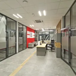 Wnętrze biura z przeszklonymi ścianami, na których umieszczono logo firmy wykonane metodą piaskowania, widoczne biurko i krzesło biurowe oraz strefa relaksu z sofami.