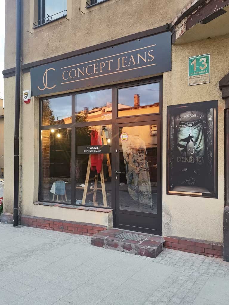 Fasada sklepu odzieżowego Concept Jeans z szyldem, plakatem i wystawą w oknie, widok z zewnątrz.