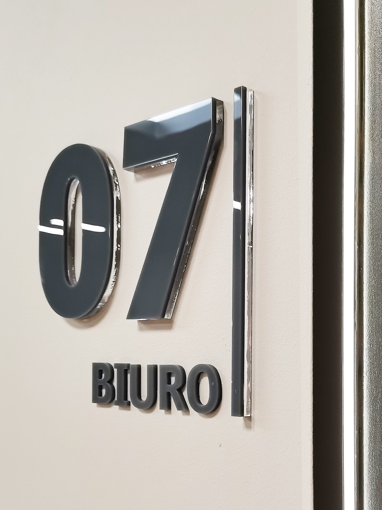 Oznakowanie biura numerem '071' i napisem 'BIURO' wykonane z szarego tworzywa, zamontowane na ścianie w Tarnowskich Górach.