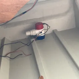 Wnętrze pomalowane na szaro z zamontowaną biało-czerwono-niebieską pompką elektryczną z podłączonymi kablami.