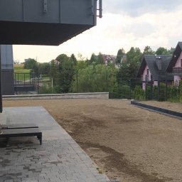 MICHAŁ GALAS GALASBRUK - Przygotowany teren pod przyszłą nawierzchnię, widoczne obrzeża, częściowo ułożona kostka brukowa, w tle domy jednorodzinne.