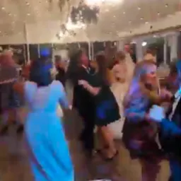 Parkiet taneczny z bawiącymi się gośćmi weselnymi, widziany z perspektywy DJ-a. Oświetlenie sceniczne i dekoracje sufitowe tworzą imprezowy klimat.