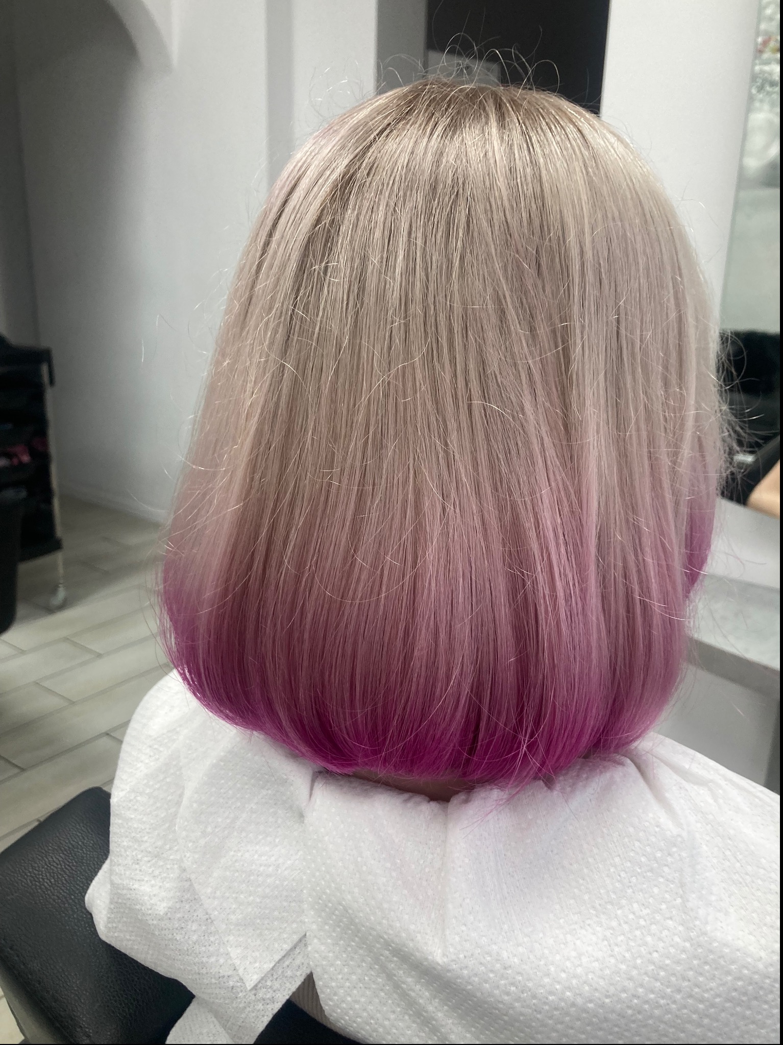 Tył głowy kobiety z włosami ombre: odcień blond przechodzi w intensywny róż, wykonany w salonie fryzjerskim w Gdyni.