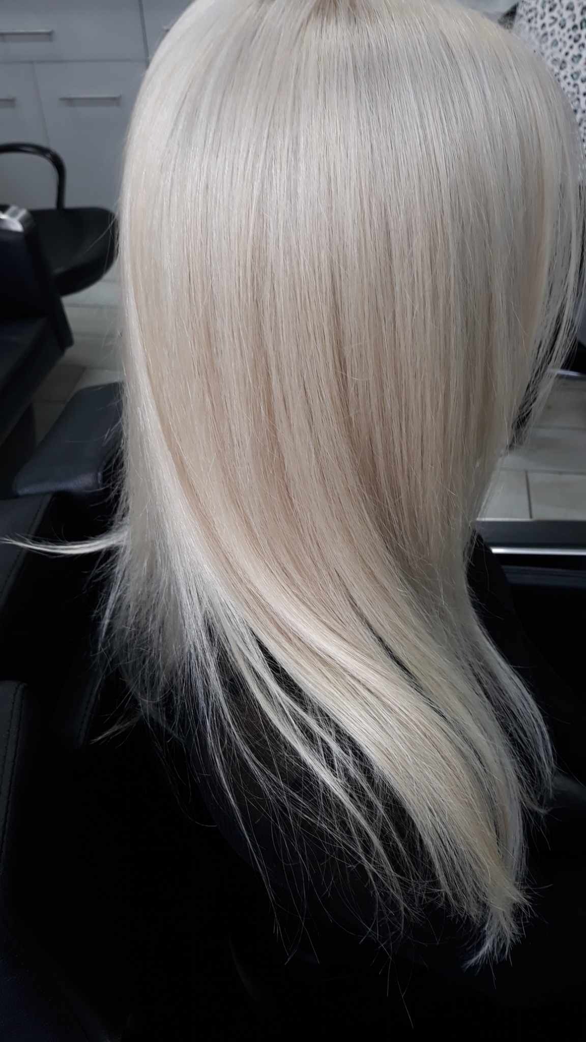 Świeżo ufarbowane platynowe blond włosy, gładkie i błyszczące, z delikatnymi refleksami w salonie fryzjerskim.