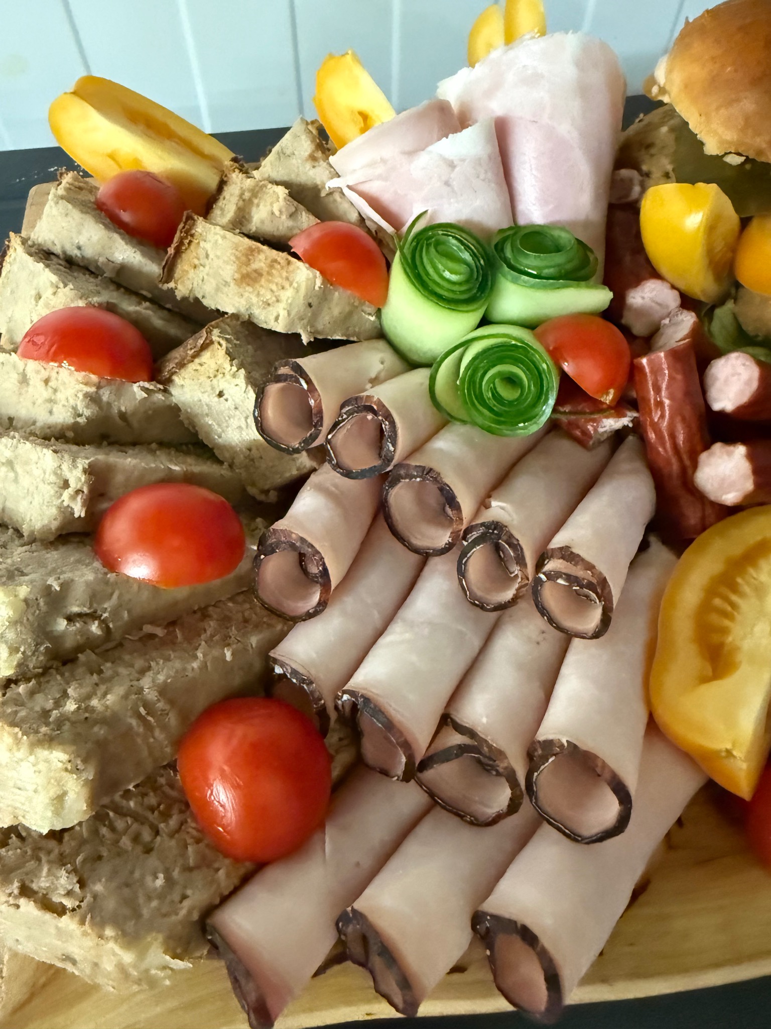 Deska przekąsek z pasztetem, roladkami z szynki, pomidorkami koktajlowymi i ogórkiem, idealna na catering firmowy lub świąteczny.