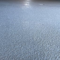 Usługi budowlane&stolarskie-Domino - Szpachlowana powierzchnia podłogi z widoczną fakturą 'baranka' i delikatnym połyskiem, świeżo po nałożeniu.