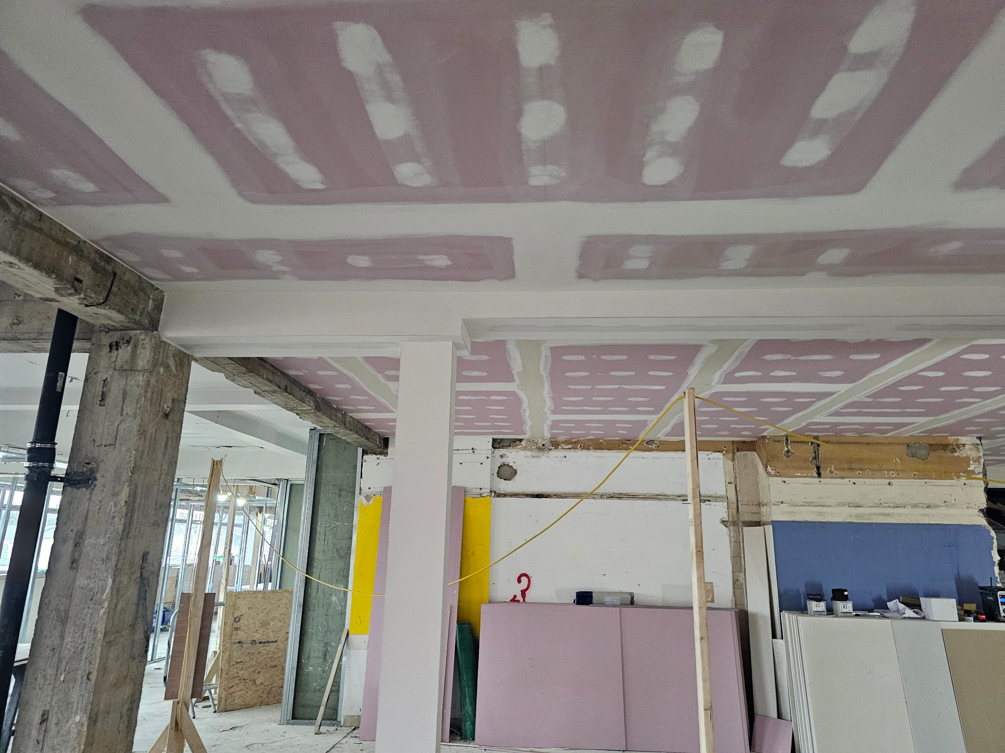 Wnętrze w Jeleniej Górze w trakcie prac wykończeniowych: widoczny sufit z płyt gipsowo-kartonowych, częściowo zaszpachlowany, oraz elementy konstrukcyjne budynku.