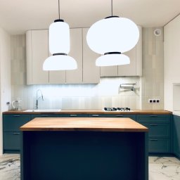 LAMAR meble - Nowoczesna kuchnia z wyspą: białe szafki górne, ciemnozielone dolne, drewniany blat, marmurowe płytki podłogowe i designerskie lampy wiszące.