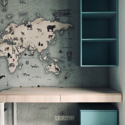 LAMAR meble - Błękitny regał wiszący nad biurkiem z jasnego drewna, na tle ściany z mapą świata w stylu vintage z motywami zwierząt i statków powietrznych.