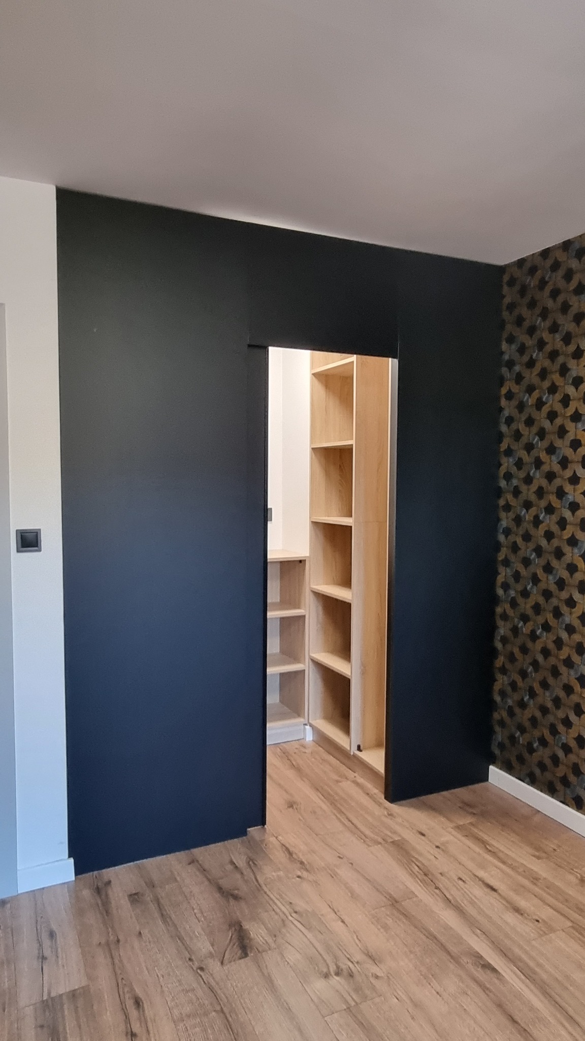 Garderoba wykonana we wnęce zamkniętą matowym akrylem z drzwiami przesuwnymi