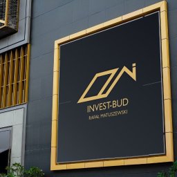 Marcin Konopnicki Portfolio - Złoty logotyp firmy Invest-Bud Rafała Matuszewskiego na czarnym tle, umieszczony w złotej ramie na elewacji budynku z elementami dekoracyjnymi w kolorze złota.