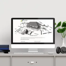 Ekran komputera stacjonarnego prezentuje stronę firmy Mar Invest z wizualizacją 3D domu na planach architektonicznych. Obok słuchawki i roślina doniczkowa.