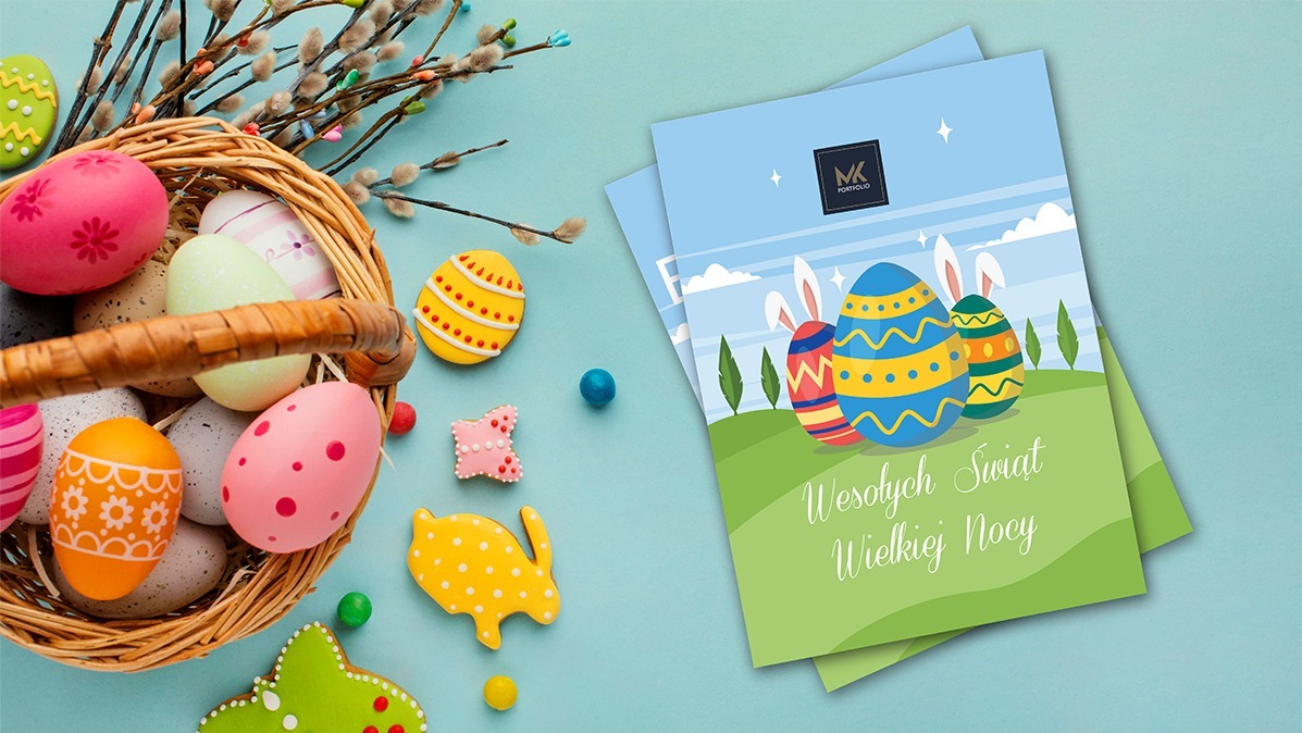 Wielkanocna kompozycja z koszykiem pełnym malowanych jajek, ciasteczek w kształcie jajek i zwierząt oraz ulotek z życzeniami świątecznymi.