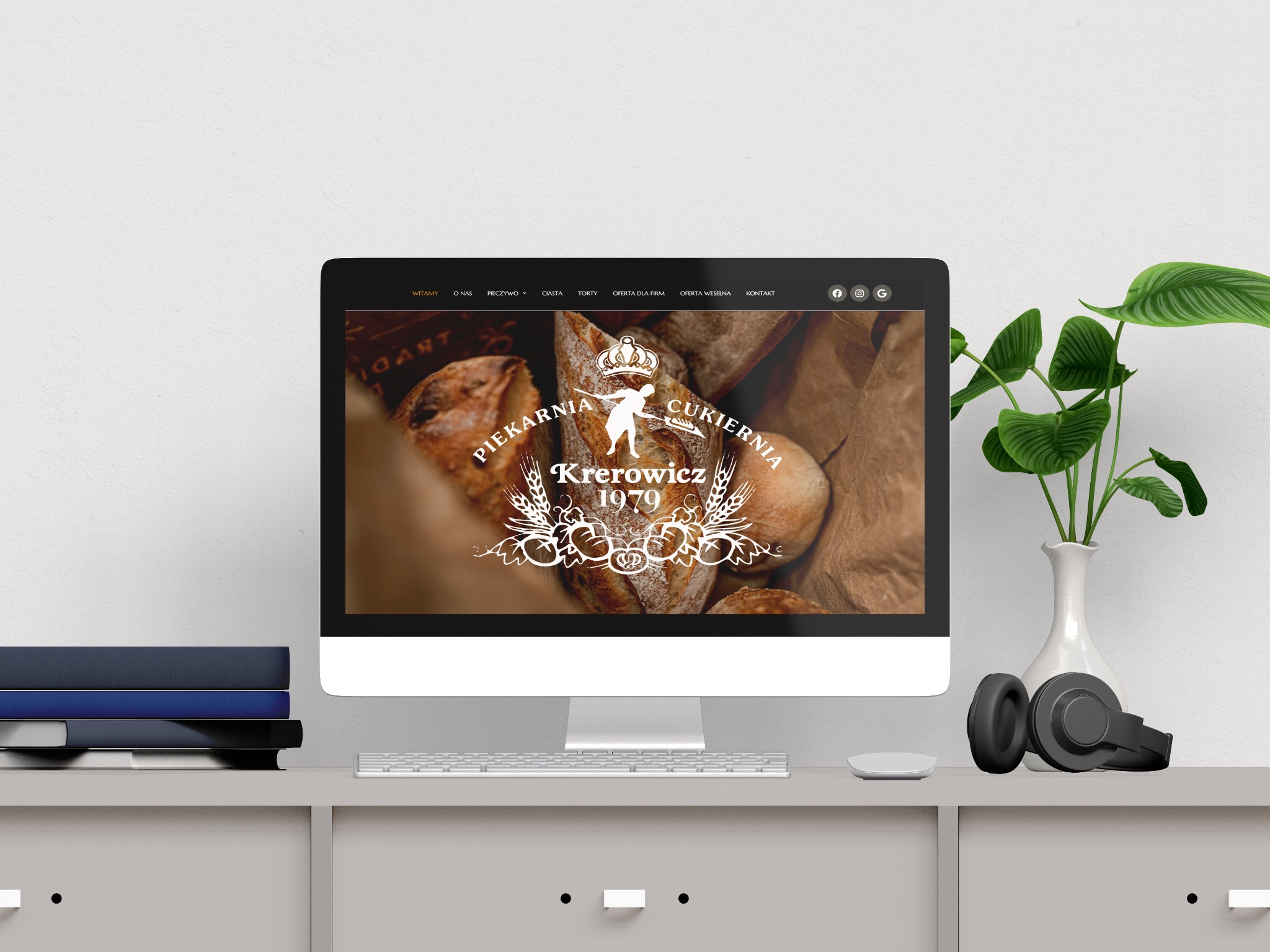 Monitor wyświetla stronę internetową piekarni Krerowicz 1979 z pieczywem w tle. W tle biurko z książkami, słuchawkami i rośliną doniczkową.