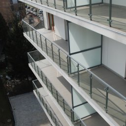 METAL-STYL Sp. z o.o. - Wielopiętrowy budynek z balkonami zabezpieczonymi szklanymi balustradami z nierdzewnymi elementami mocującymi, widok z góry.