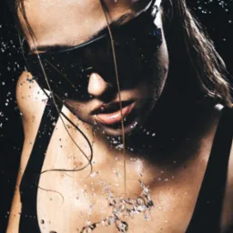 Mokra twarz kobiety w okularach przeciwsłonecznych, krople wody na skórze i włosach, ciemne tło, ujęcie z góry, dynamiczne i artystyczne.