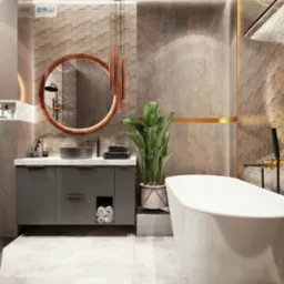 Nowoczesna łazienka z wolnostojącą białą wanną, szarą szafką pod umywalką i okrągłym lustrem z podświetleniem, uzupełniona rośliną w doniczce i dekoracyjnym oświetleniem wiszącym.