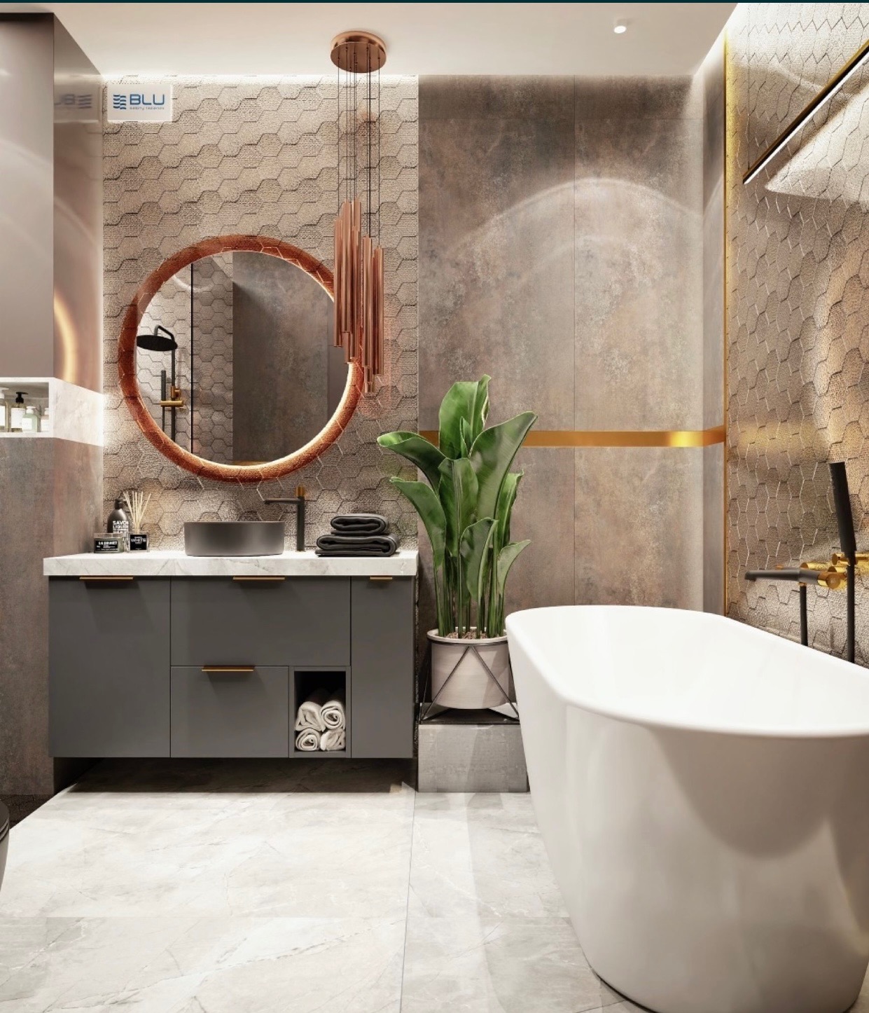 Nowoczesna łazienka z wolnostojącą białą wanną, szarą szafką pod umywalką i okrągłym lustrem z podświetleniem, uzupełniona rośliną w doniczce i dekoracyjnym oświetleniem wiszącym.
