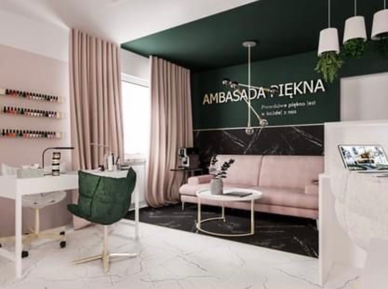 Wnętrze salonu kosmetycznego z recepcją, poczekalnią z pudrową sofą i stanowiskiem do manicure z zielonym krzesłem, oświetlone nowoczesną lampą i wiszącymi doniczkami z roślinami.
