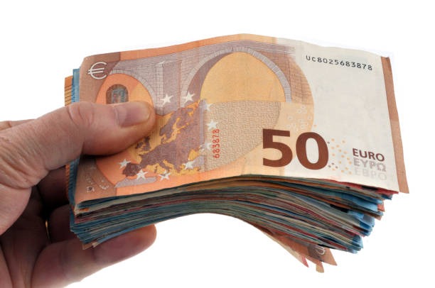 Dłoń trzymająca plik banknotów 50 euro, widoczne numery seryjne na wierzchu banknotu.