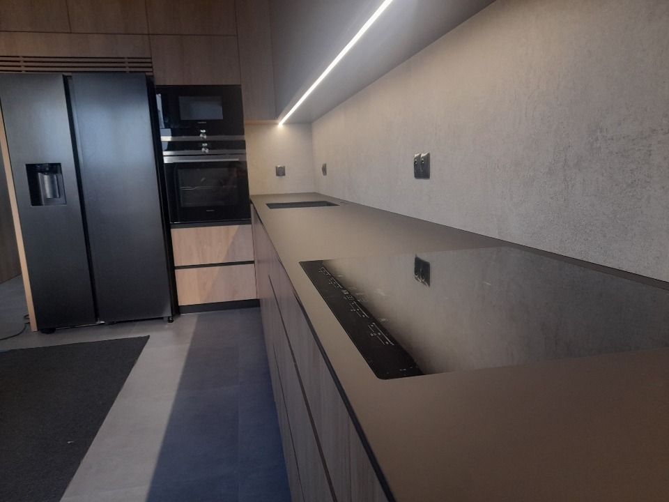 Nowoczesna kuchnia na wymiar w Warszawie z czarnym blatem i sprzętem AGD, widok z perspektywy blatu.