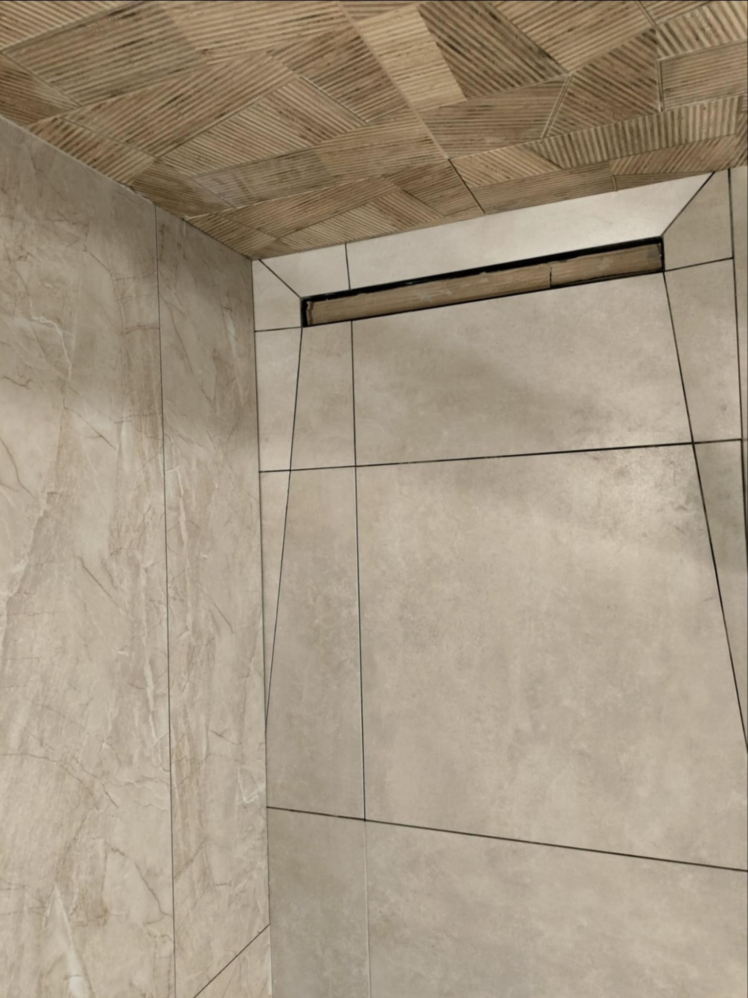Nowoczesna łazienka z beżowymi płytkami imitującymi marmur na ścianie i podłodze, oraz drewnopodobnymi płytkami na suficie, z odpływem liniowym w podłodze
