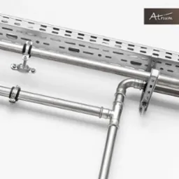 Metalowe rury wentylacyjne z mocowaniami na tle białej ściany, widoczne logo firmy Atrium w prawym górnym rogu.