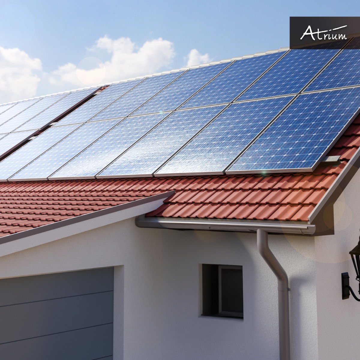 Dom jednorodzinny z panelami fotowoltaicznymi na czerwonym dachu, widoczny fragment garażu i lampa zewnętrzna, logo firmy w prawym górnym rogu.