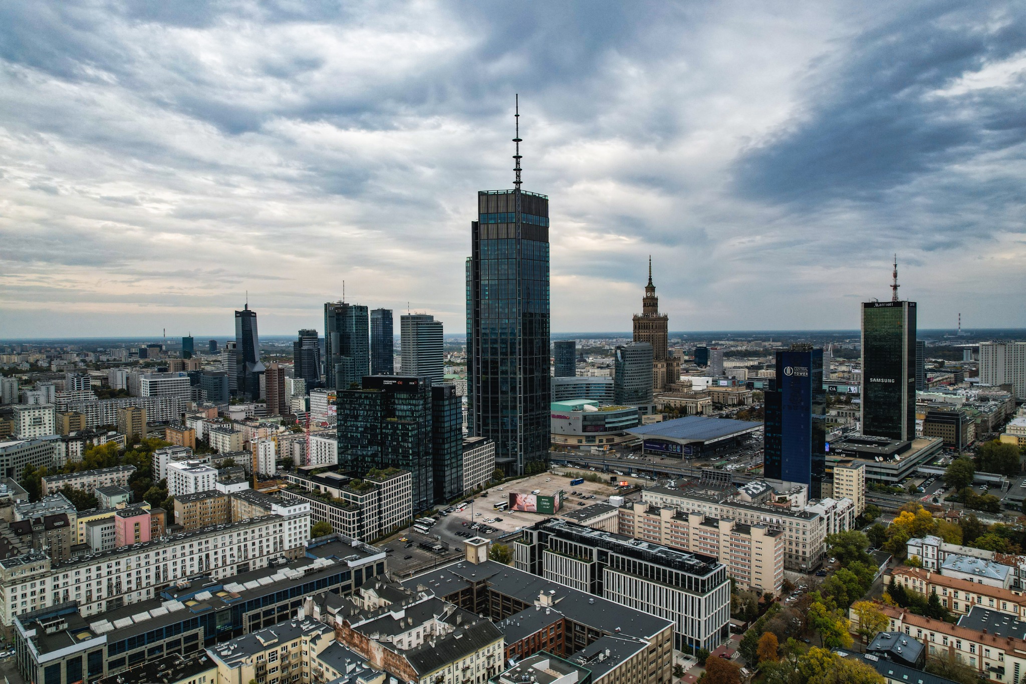 Panorama Warszawy z lotu ptaka, widok na drapacze chmur w pochmurny dzień, w tle Pałac Kultury i Nauki.