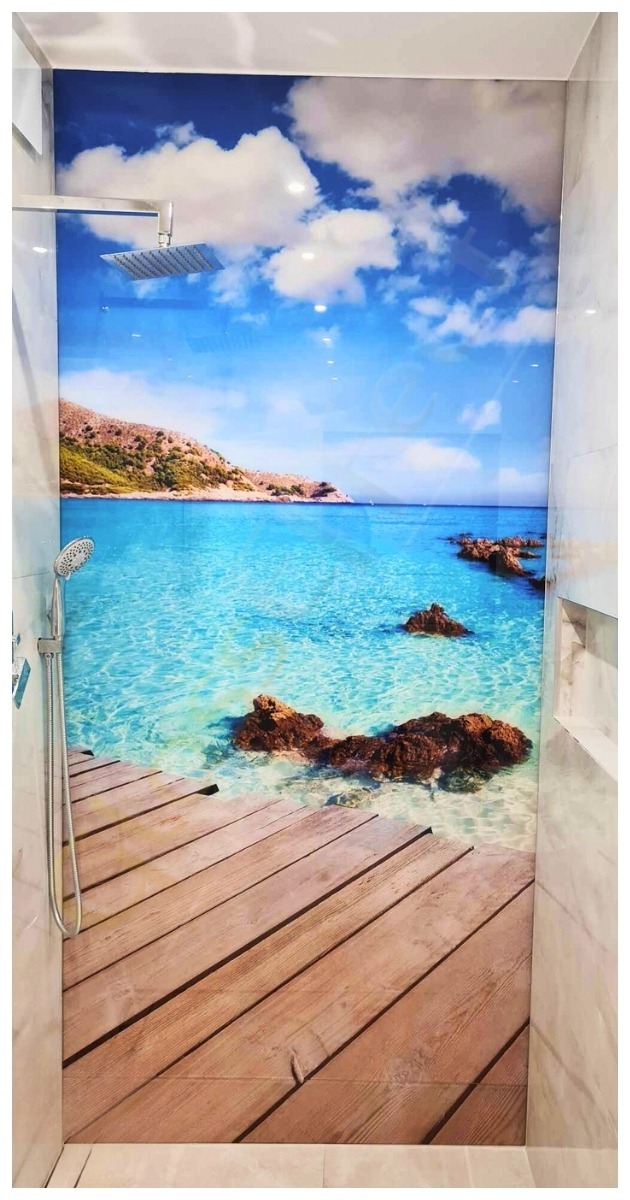 Kabina prysznicowa z fototapetą przedstawiającą tropikalny krajobraz: drewniany pomost przechodzący w turkusową wodę z widokiem na wyspę i błękitne niebo z chmurami.