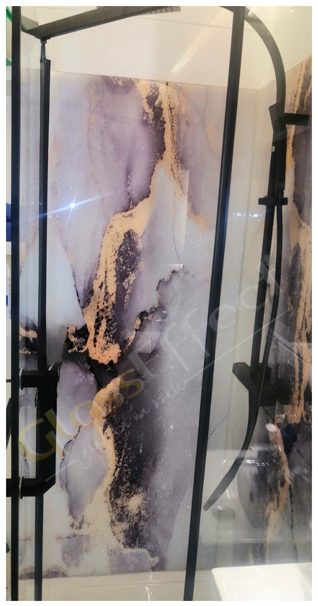 Szklana kabina prysznicowa z czarnymi profilami i dekoracyjną grafiką imitującą marmur w odcieniach bieli, szarości i złota.