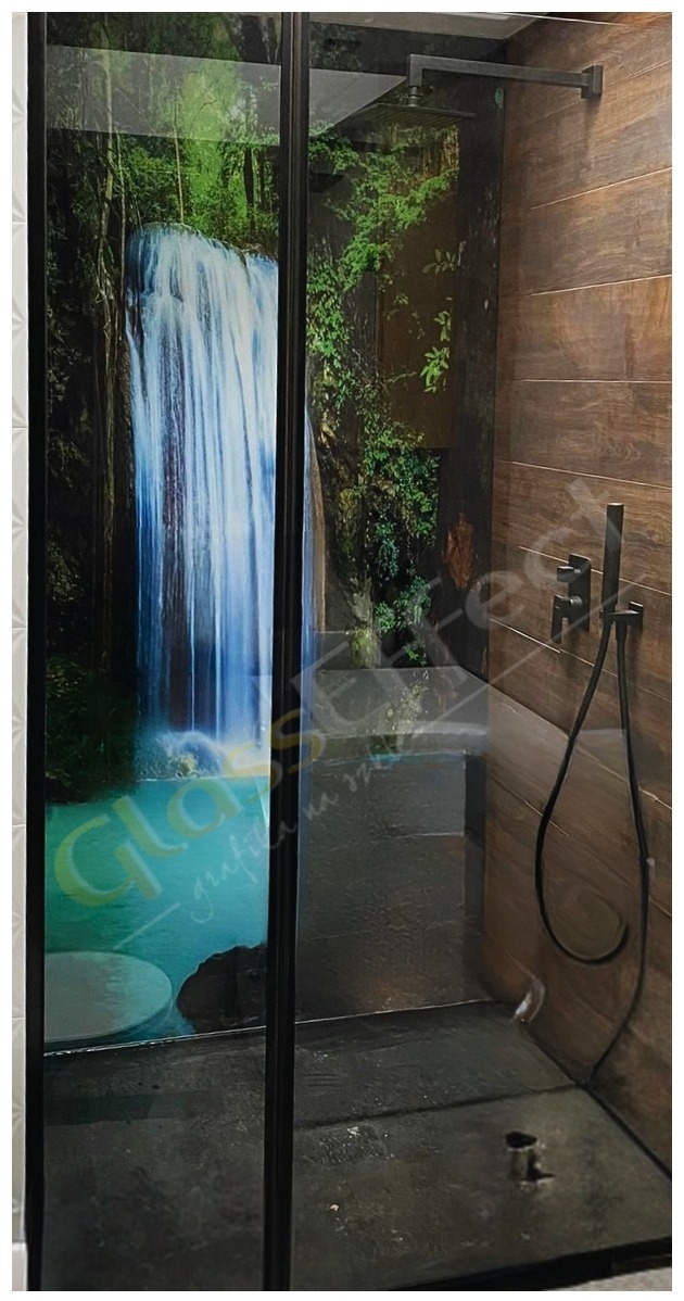 Kabina prysznicowa z czarnymi ramami i szklanymi drzwiami z fototapetą przedstawiającą wodospad w tropikalnym lesie, zamontowana na tle ściany wyłożonej drewnopodobnymi płytkami.