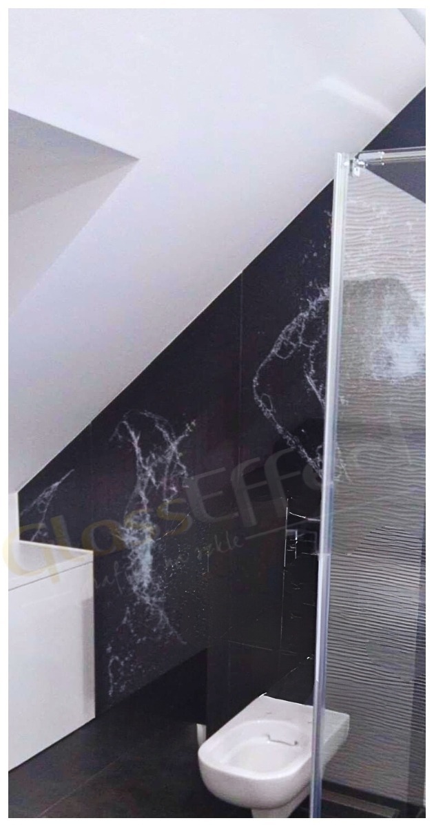 Nowoczesna kabina prysznicowa z drzwiami szklanymi z Radomska, z widoczną czarną ścianą z efektem marmuru i białą armaturą w łazience na poddaszu.