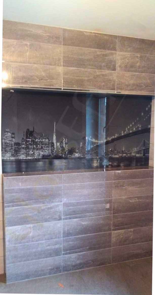 Szklany panel ścienny z motywem panoramy nocnego miasta, wkomponowany pomiędzy płytki imitujące kamień.