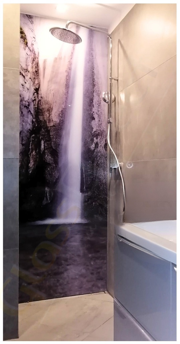 Szklana ściana prysznicowa z motywem wodospadu, chromowana bateria natryskowa i szara obudowa wanny w nowoczesnej łazience.