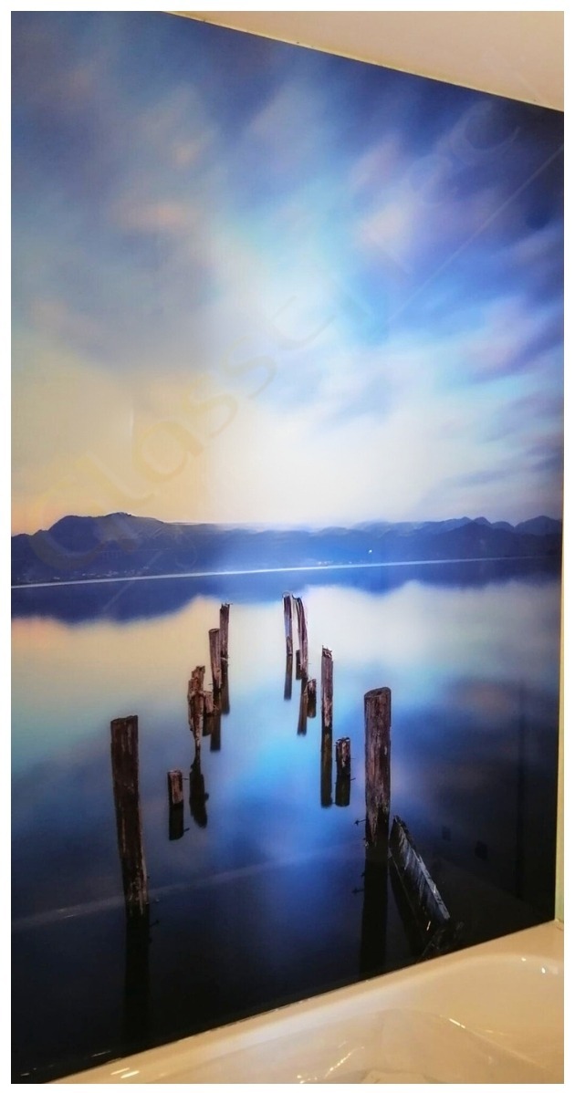 Szklana ściana w łazience z nadrukiem krajobrazu jeziora i starych pomostów odbijających się w wodzie, zamontowana nad wanną.