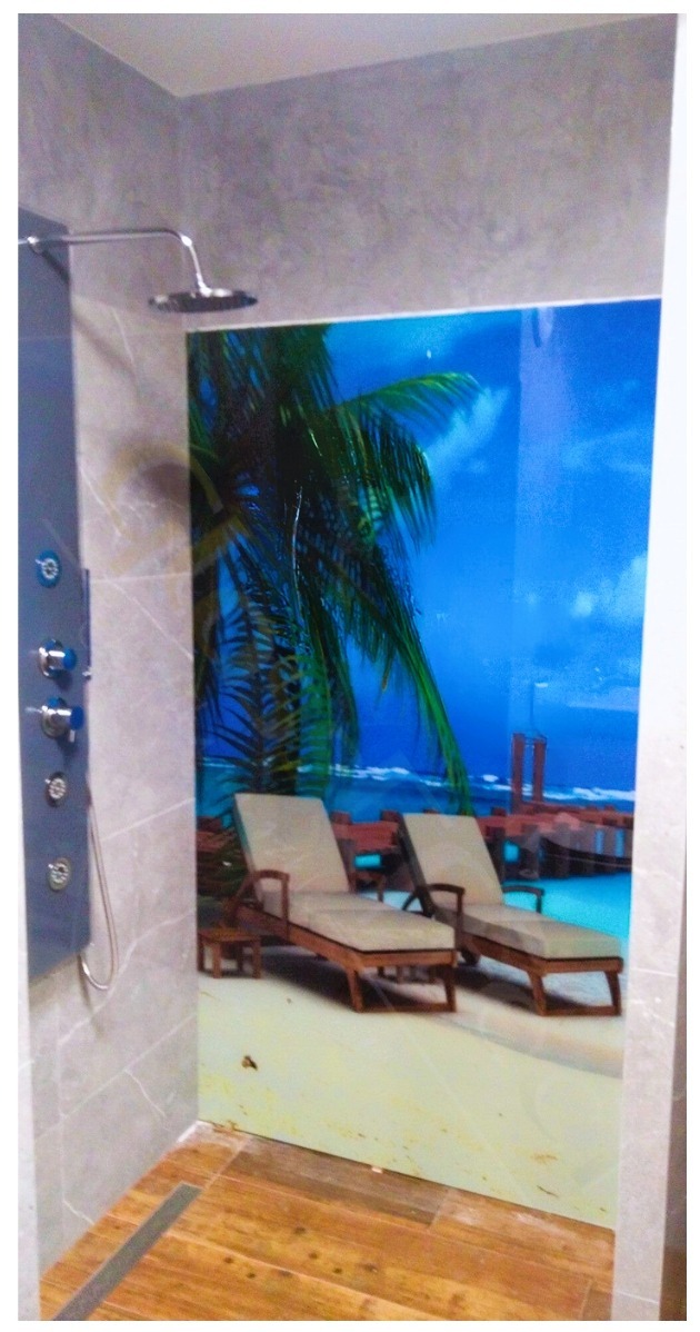 Szklana kabina prysznicowa z nadrukiem przedstawiającym plażę z leżakami i palmami, zamontowana w łazience z szarą armaturą i drewnopodobną podłogą.