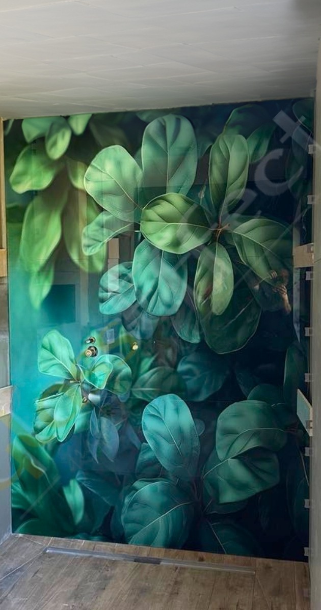 Szklane drzwi z nadrukowanym motywem dużych zielonych liści, widoczne metalowe okucia i klamka.