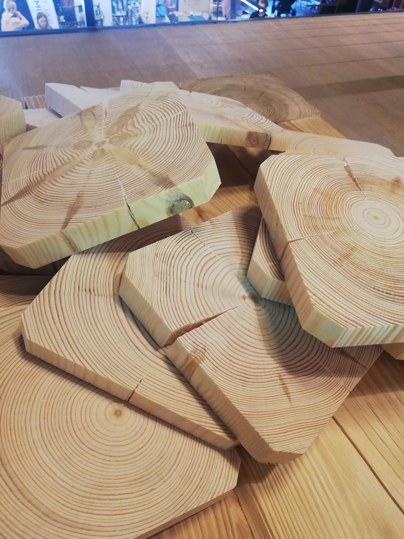 Drewniane plastry z widocznymi słojami ułożone na drewnianej podłodze, tworzące dekoracyjny wzór.