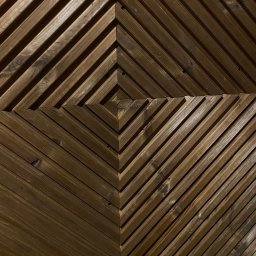 S.EnergyBud Dawid Suduł - Drewniana ściana z desek ułożonych w geometryczny wzór rombów, z widocznymi śrubami mocującymi, w ciepłej tonacji brązu.