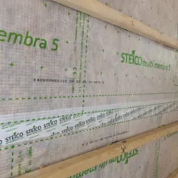 Izolacja przeciwwiatrowa STEICO multi membra 5 zamontowana na drewnianej konstrukcji szkieletowej ściany, zabezpieczona taśmą uszczelniającą STEICO multi tape P.