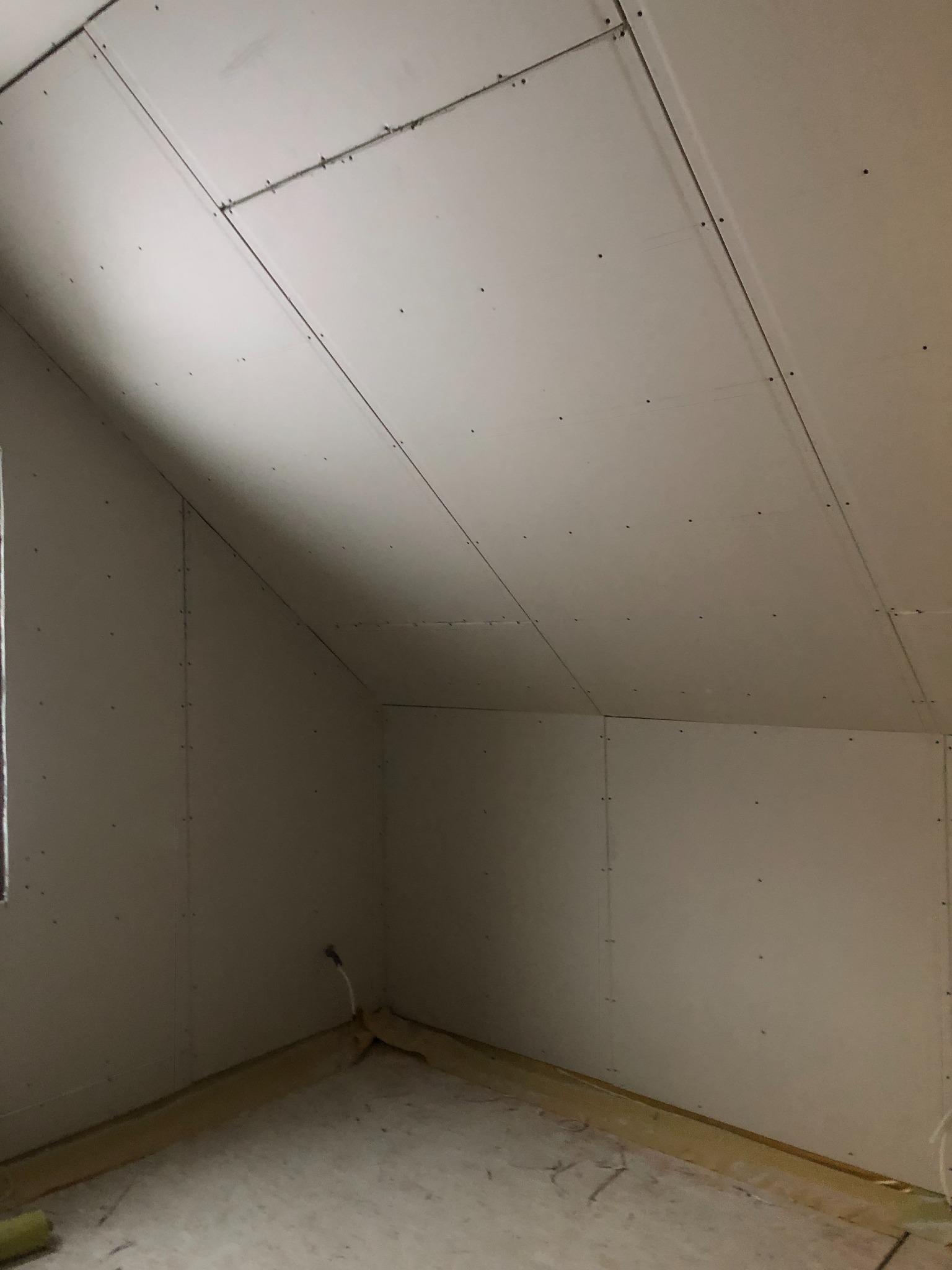 Poddasze z ukończonymi ścianami i sufitem z płyt kartonowo-gipsowych, widoczne łączenia i wkręty, przygotowane do dalszych prac wykończeniowych.